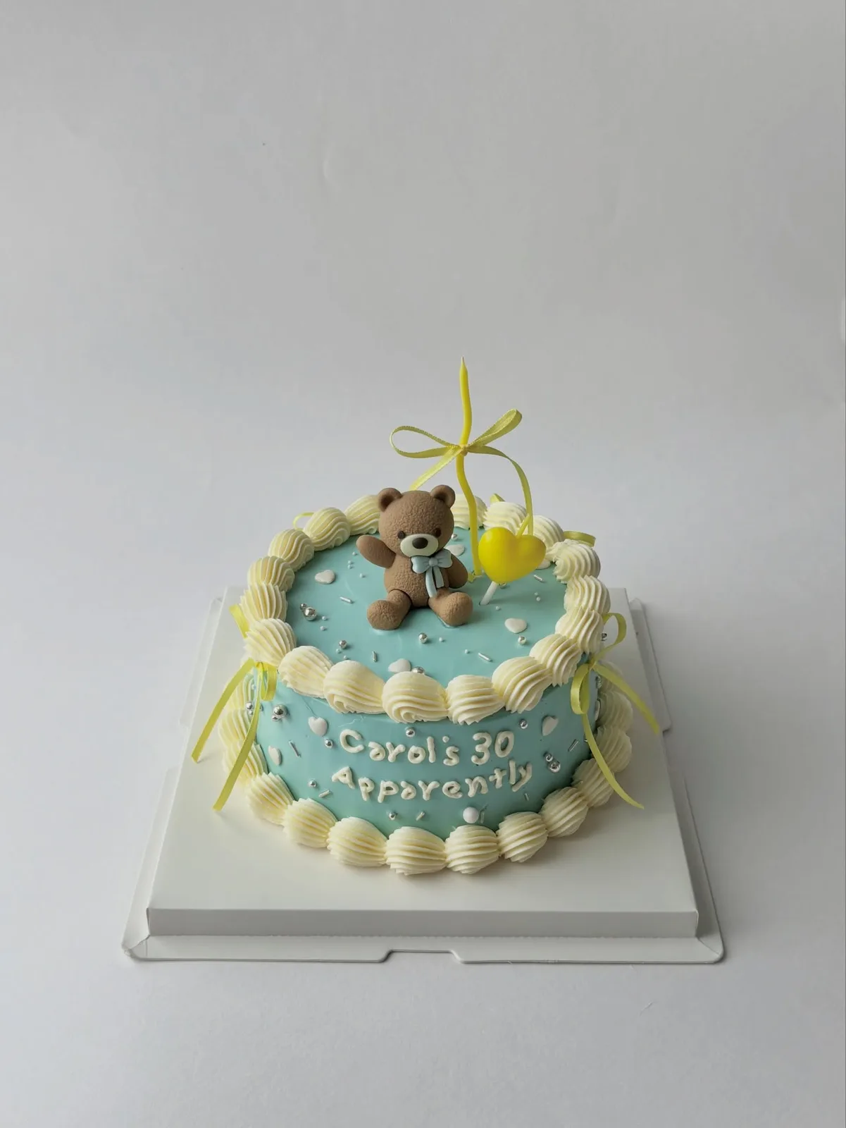 Blue cake with teddy bear, yellow bow and piped border, handmade to order by Danine Cakes in Streatham, South London