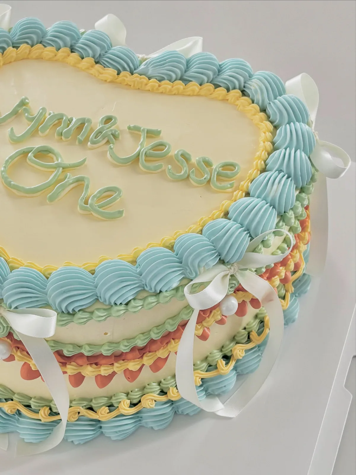 Blue heart cake with multicoloured piped borders, bespoke celebration cake from Danine Cakes, South London