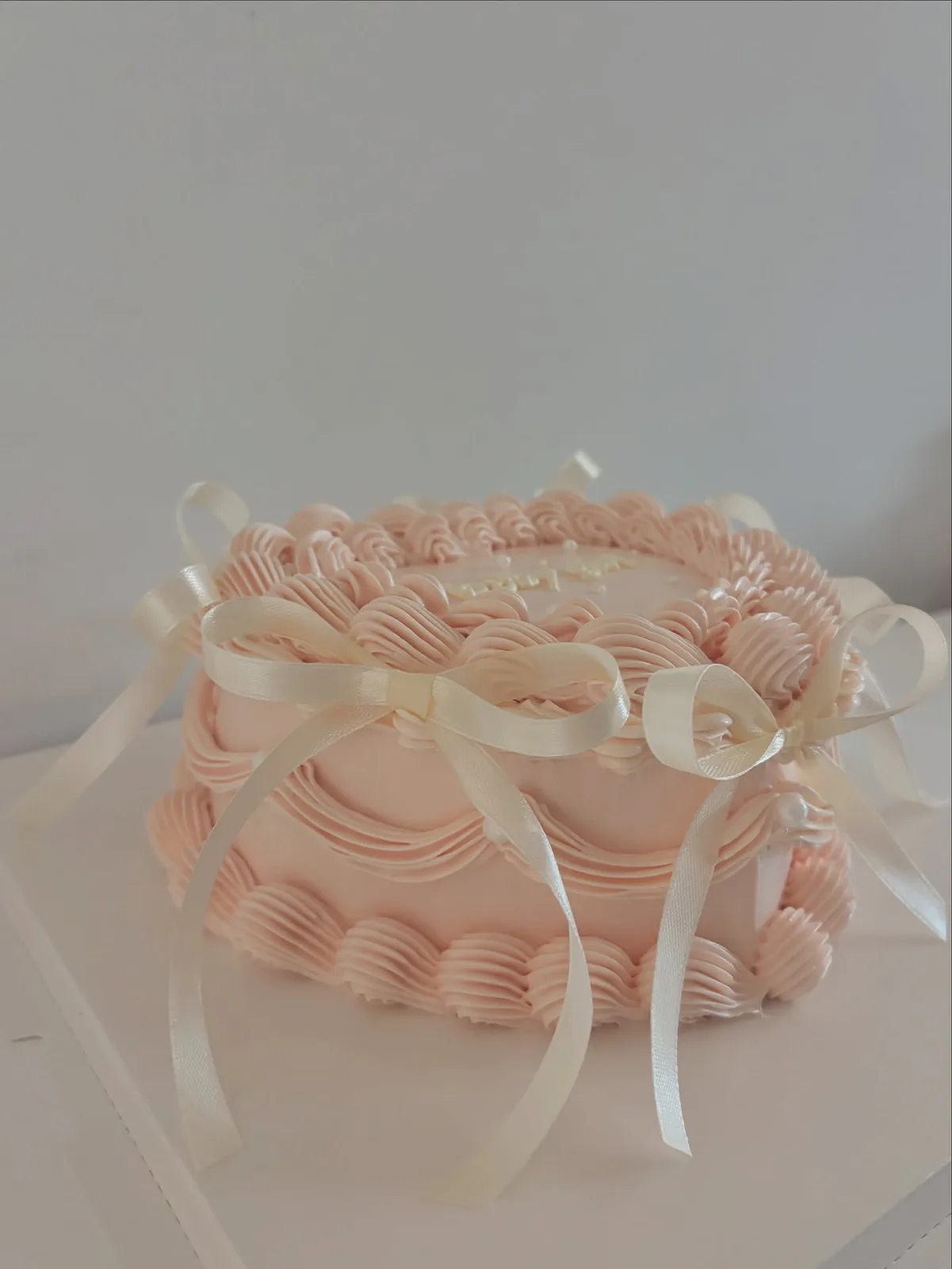 Blush pink piped ruffle cake with ribbon, handmade to order by Danine Cakes in Streatham, South London