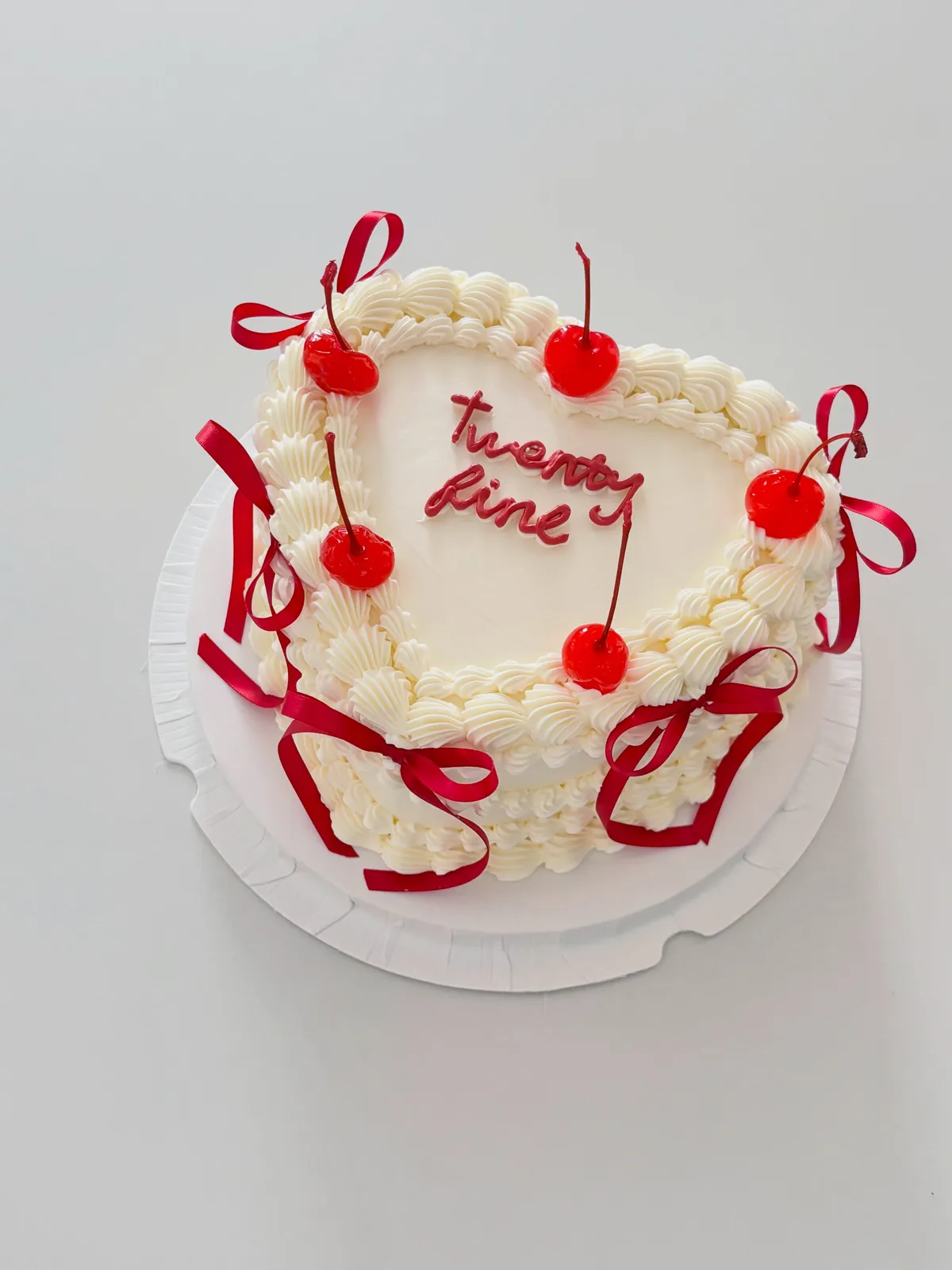 Cream cake with cherries and red ribbon bows, bespoke celebration cake from Danine Cakes, South London