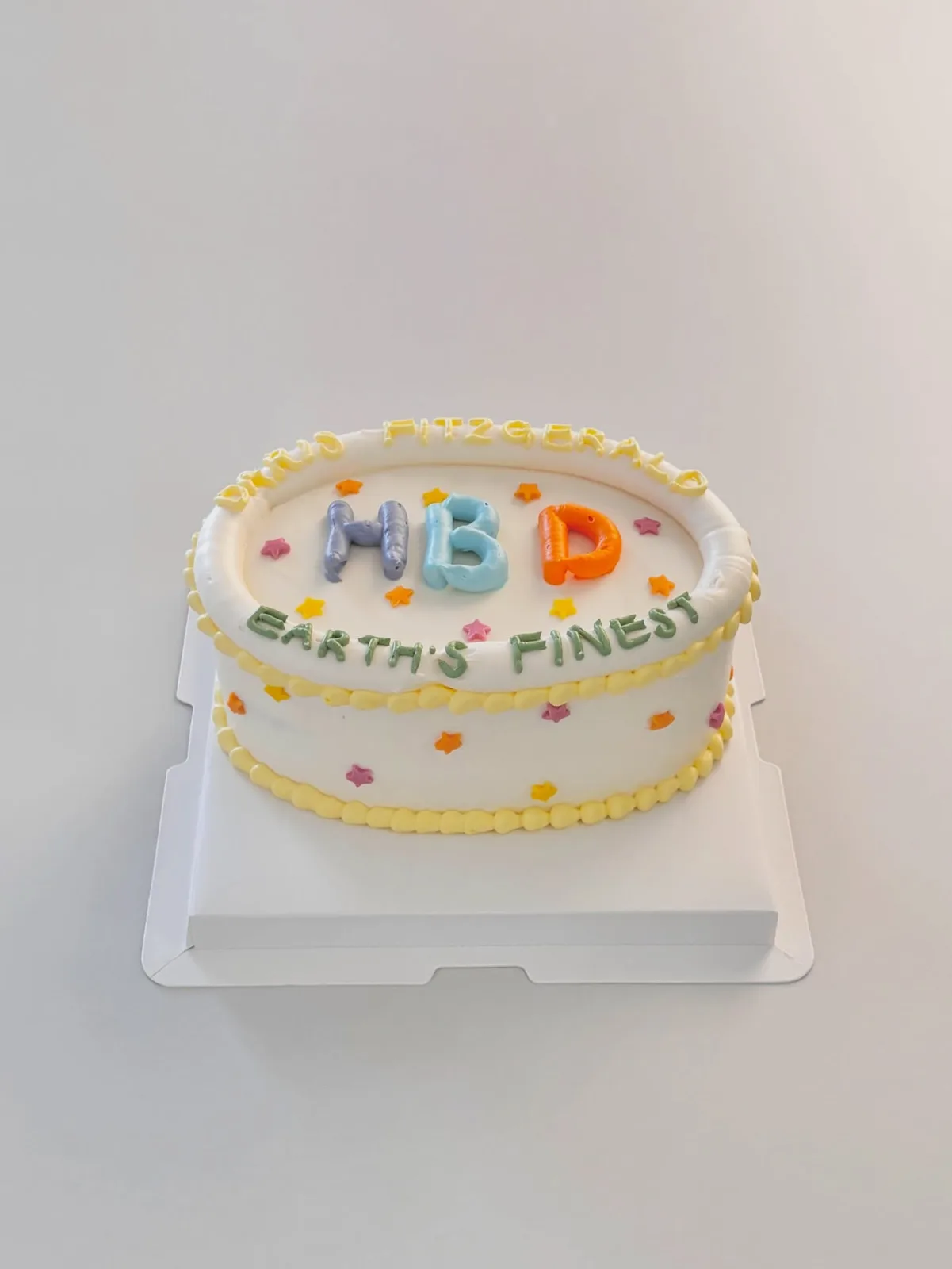 Cream lettering cake with pastel piped border, bespoke celebration cake from Danine Cakes, South London
