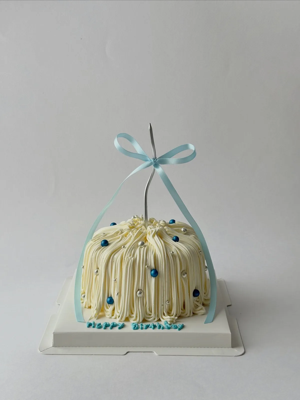 Cream piped strand cake with blue ribbon and pearls, custom cake made in Streatham SW16 - Danine Cakes