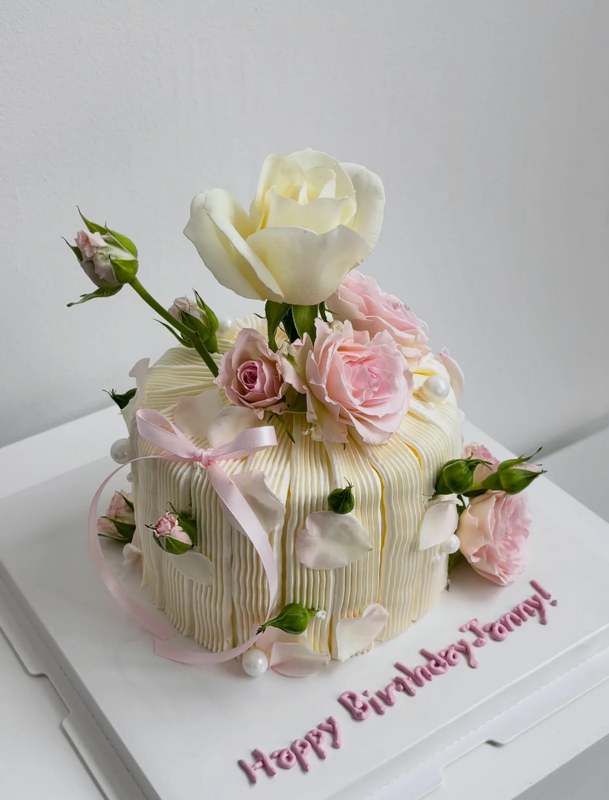 Cream piped strand cake with fresh roses and white rose, handmade to order by Danine Cakes in Streatham, South London