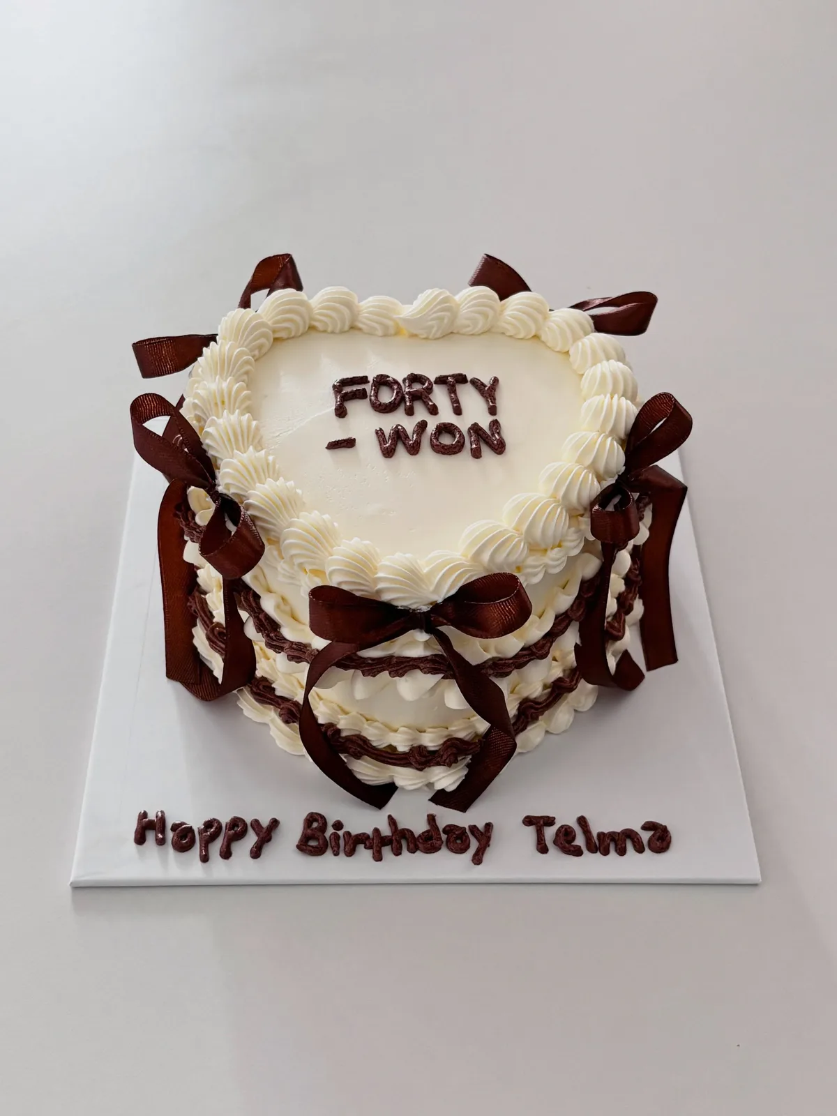 Ivory heart cake with brown bows and piped lettering, Korean-inspired custom cake handmade in Streatham, London