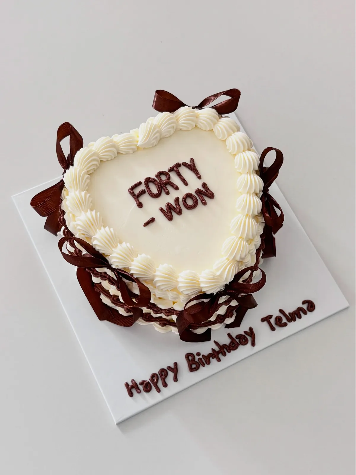 Ivory heart cake with brown bows and piped name, custom cake made in Streatham SW16 - Danine Cakes