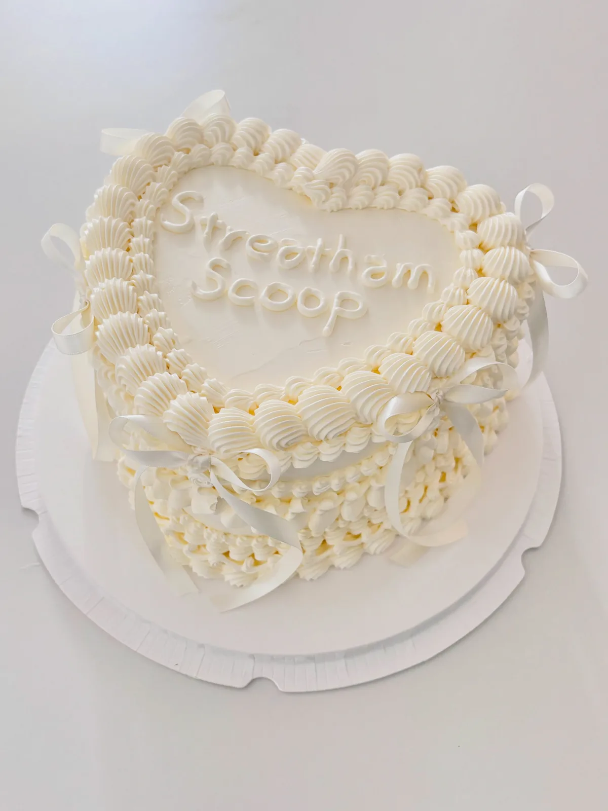 Ivory heart cake with piped lettering and bows, handmade to order by Danine Cakes in Streatham, South London