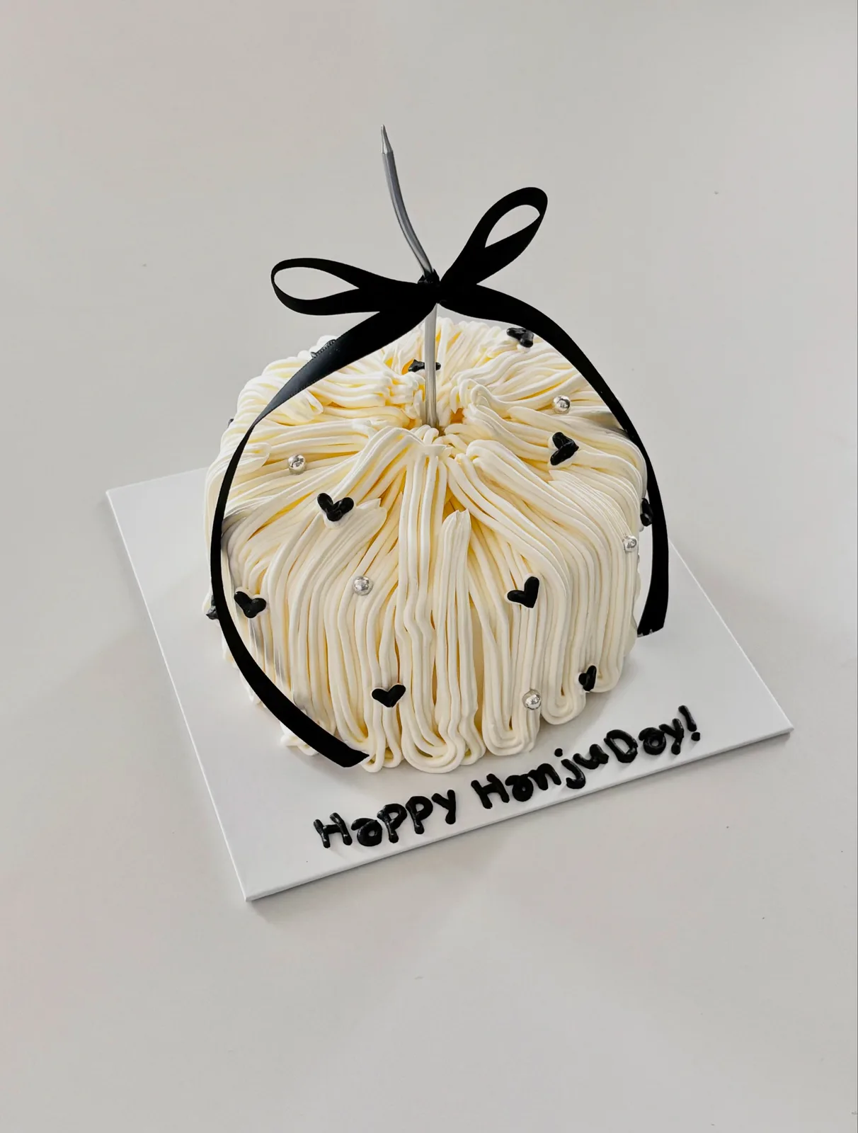 Ivory piped dome cake with black bow and hearts, bespoke celebration cake from Danine Cakes, South London