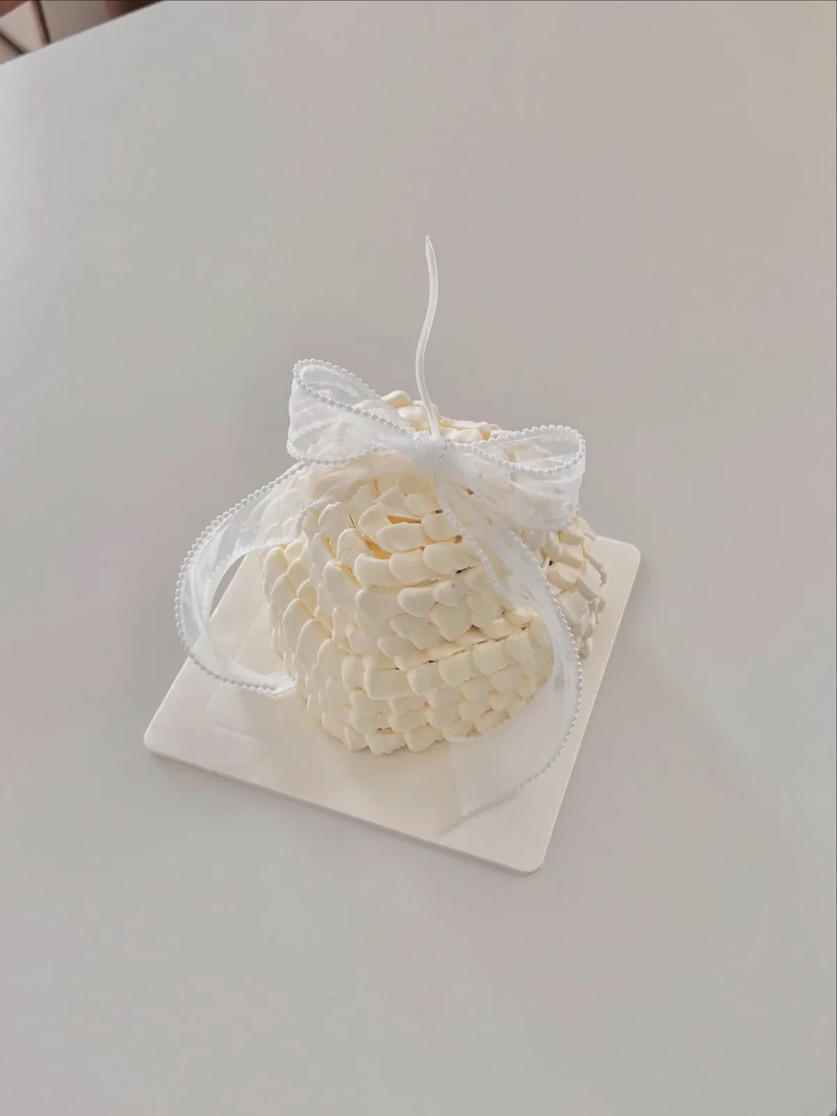 Ivory piped dome cake with organza bow, bespoke celebration cake from Danine Cakes, South London