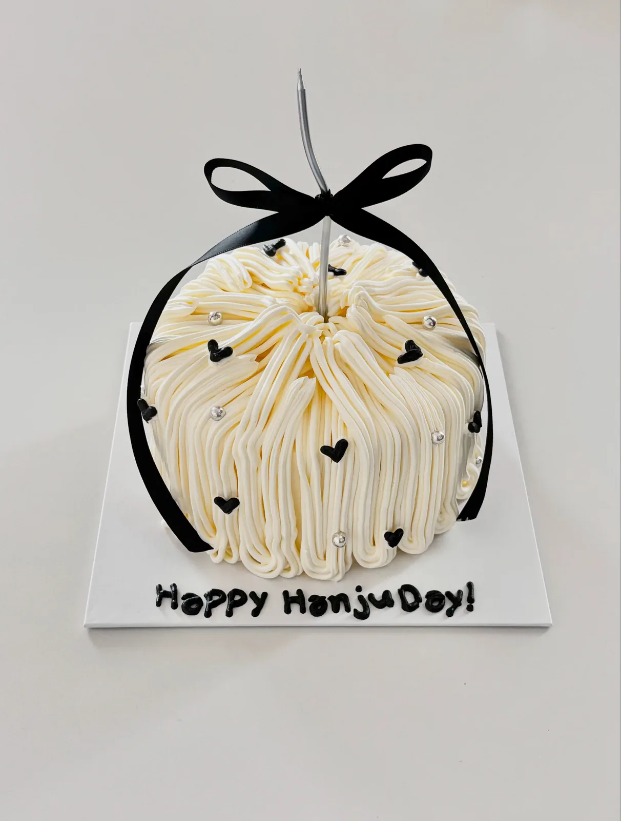 Ivory piped strand cake with black bow and hearts, handmade to order by Danine Cakes in Streatham, South London