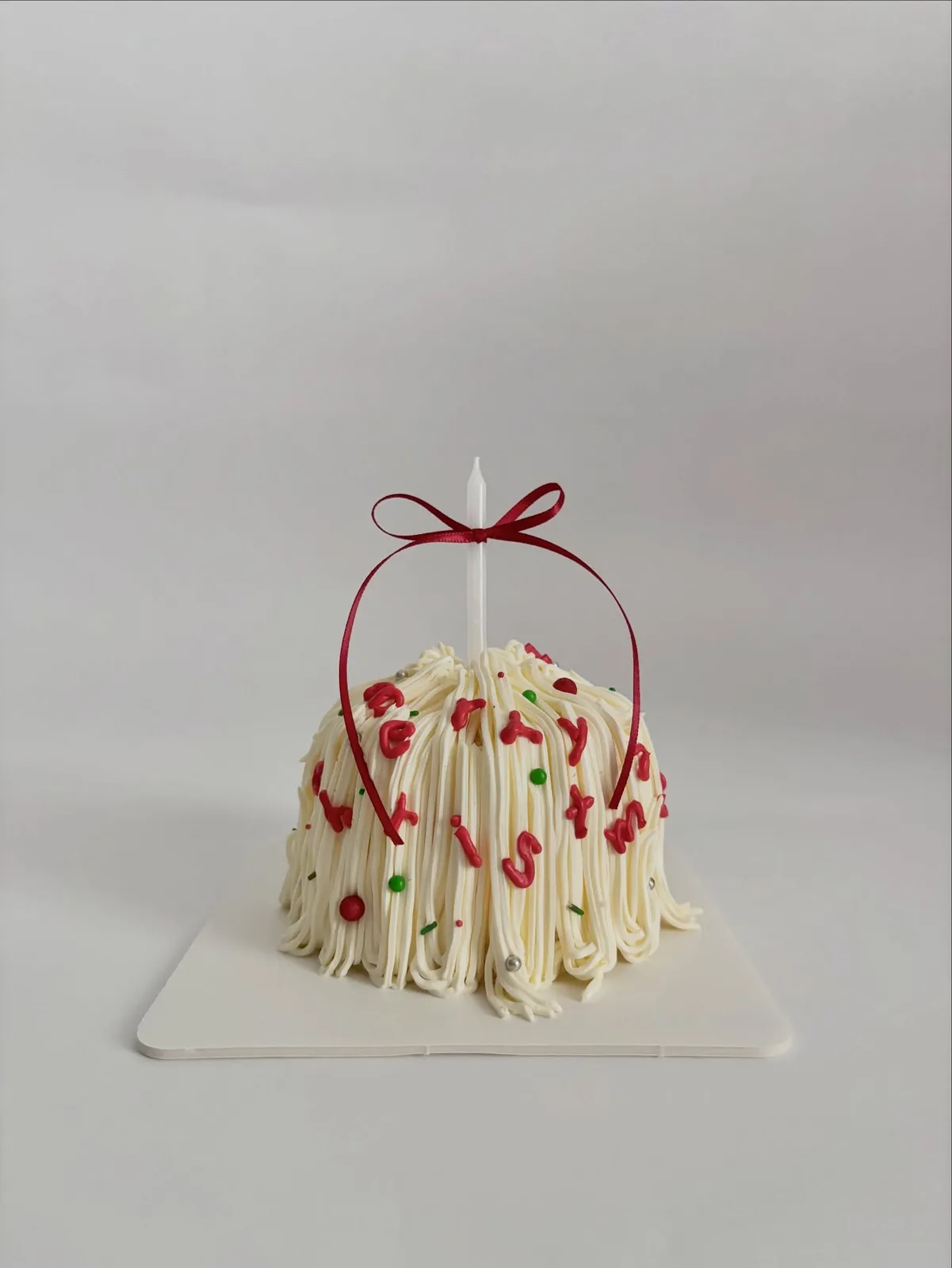 Ivory piped strand cake with red ribbon and berries, handmade to order by Danine Cakes in Streatham, South London