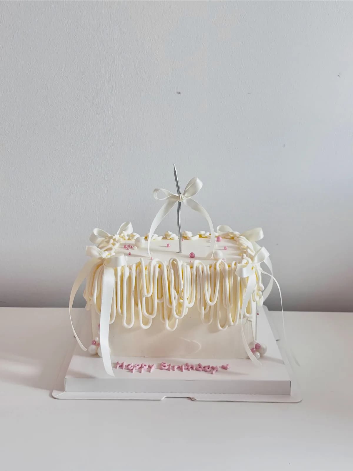 Ivory piped strand cake with white ribbon, handmade to order by Danine Cakes in Streatham, South London