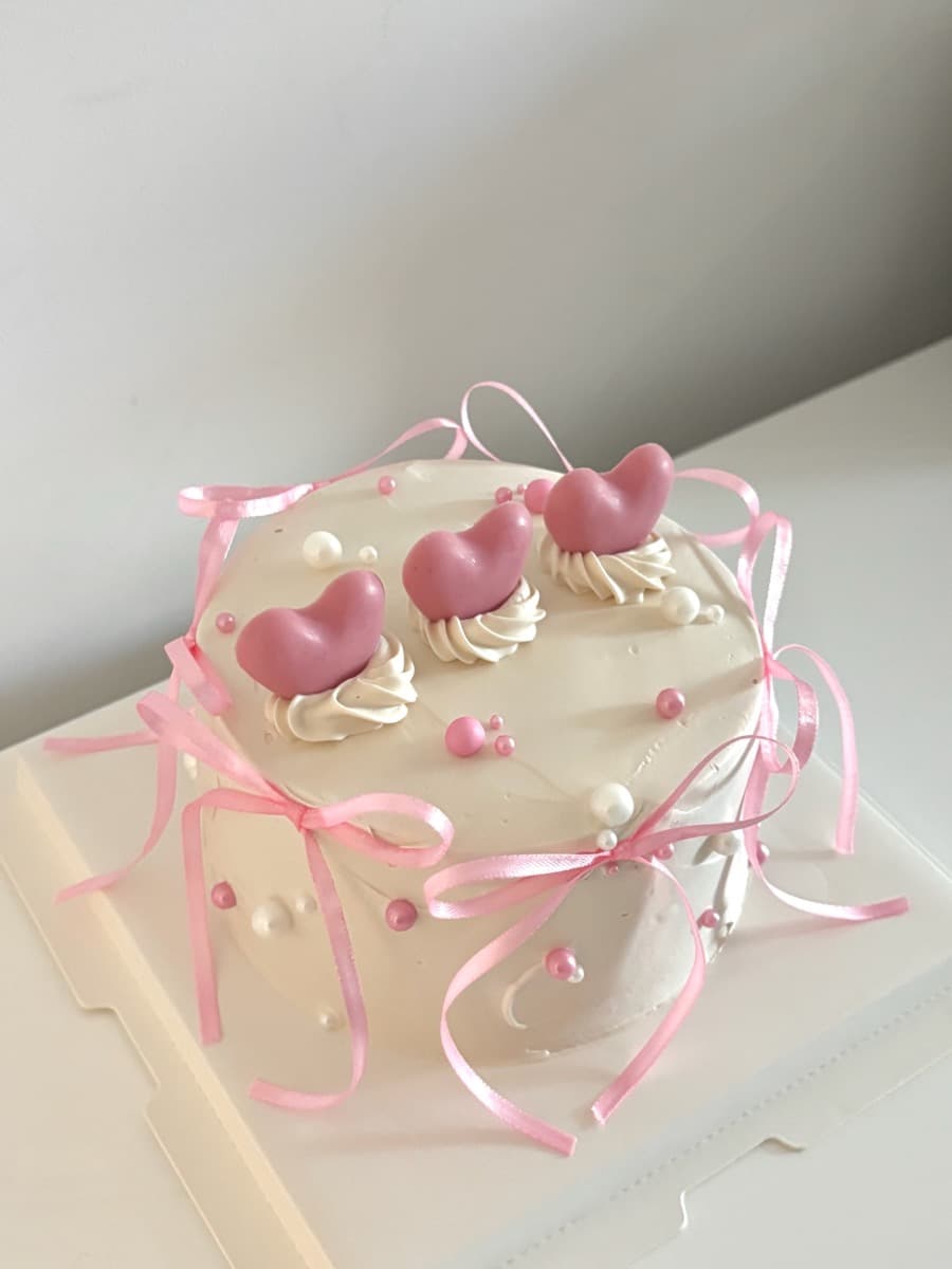 White heart cake with pink ribbon bows