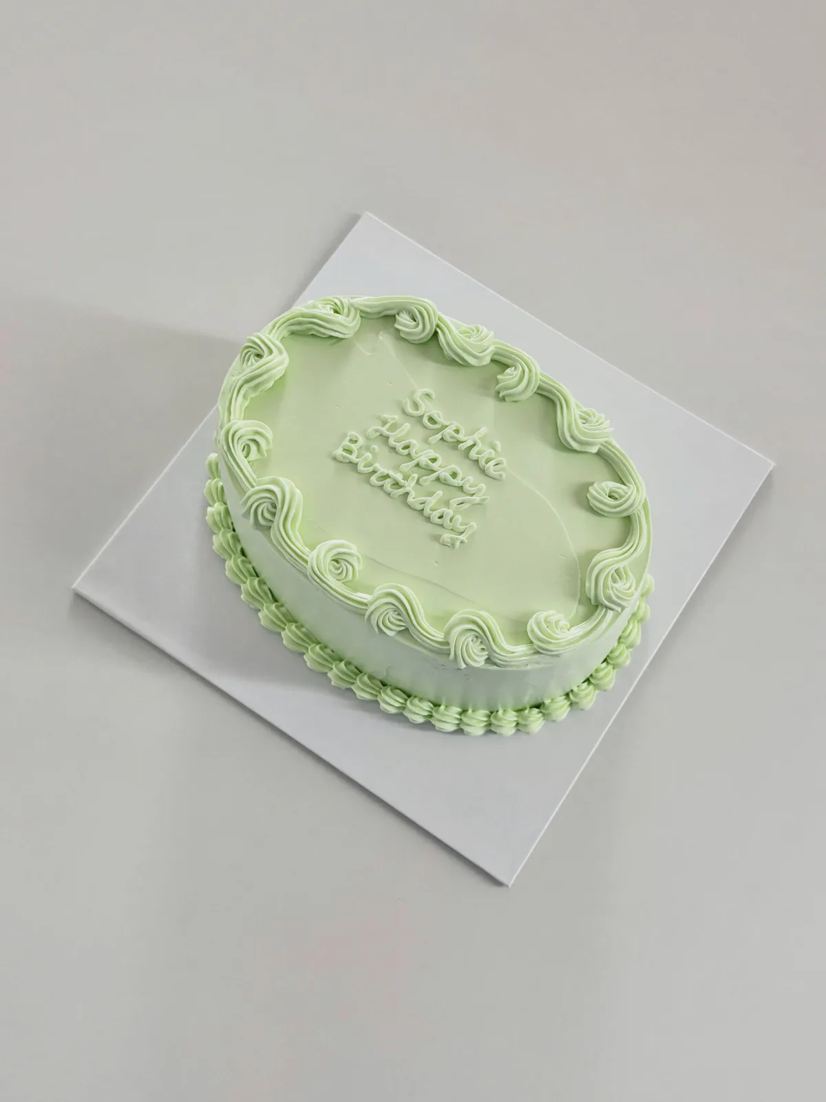 Mint green cake with piped lettering and shell border, bespoke celebration cake from Danine Cakes, South London