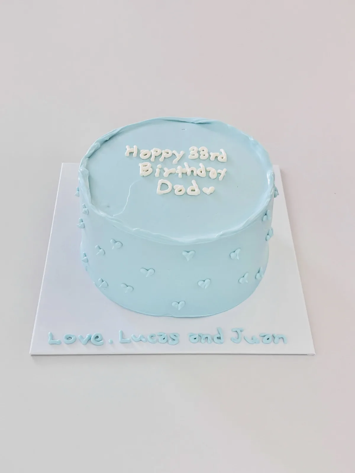 Pale blue cake with white dots and piped lettering, handmade to order by Danine Cakes in Streatham, South London