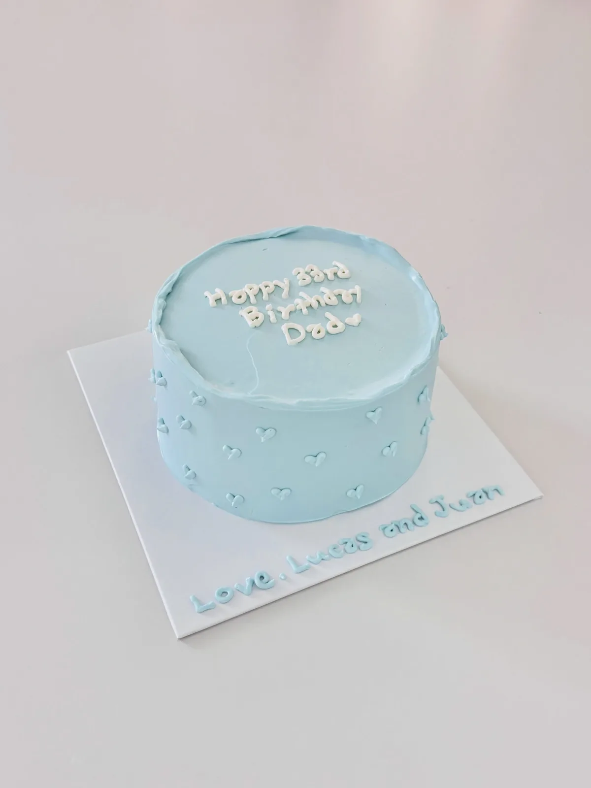Pale blue cake with white dots and piped message, bespoke celebration cake from Danine Cakes, South London