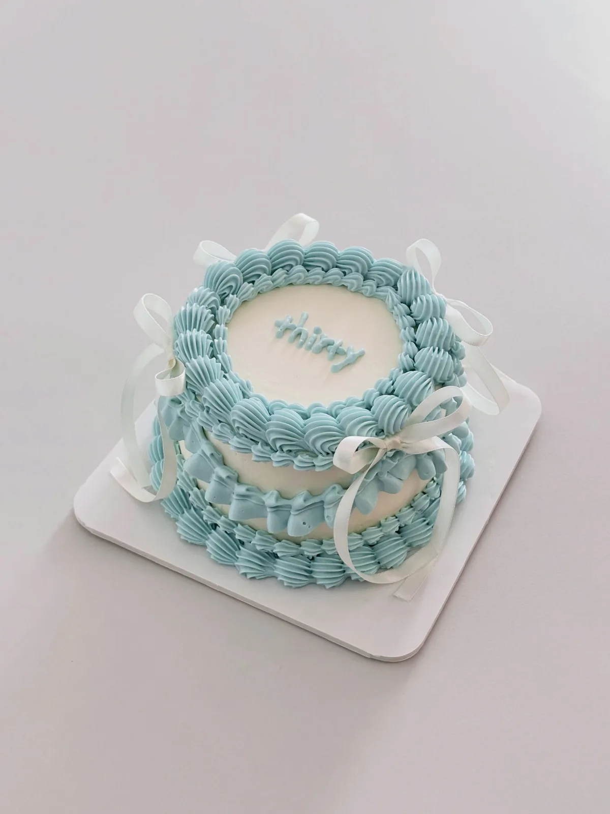 Pale blue layered cake with piped shells, bespoke celebration cake from Danine Cakes, South London