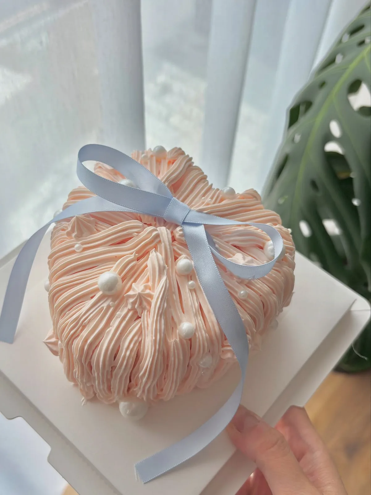 Peach piped strand cake with blue satin ribbon and pearls, handmade to order by Danine Cakes in Streatham, South London