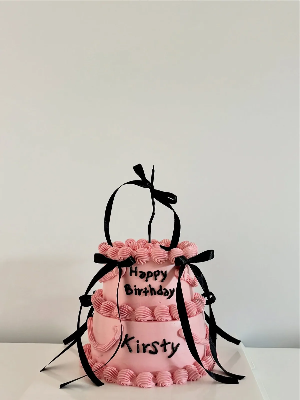 Pink piped dome cake with black bows, handmade to order by Danine Cakes in Streatham, South London
