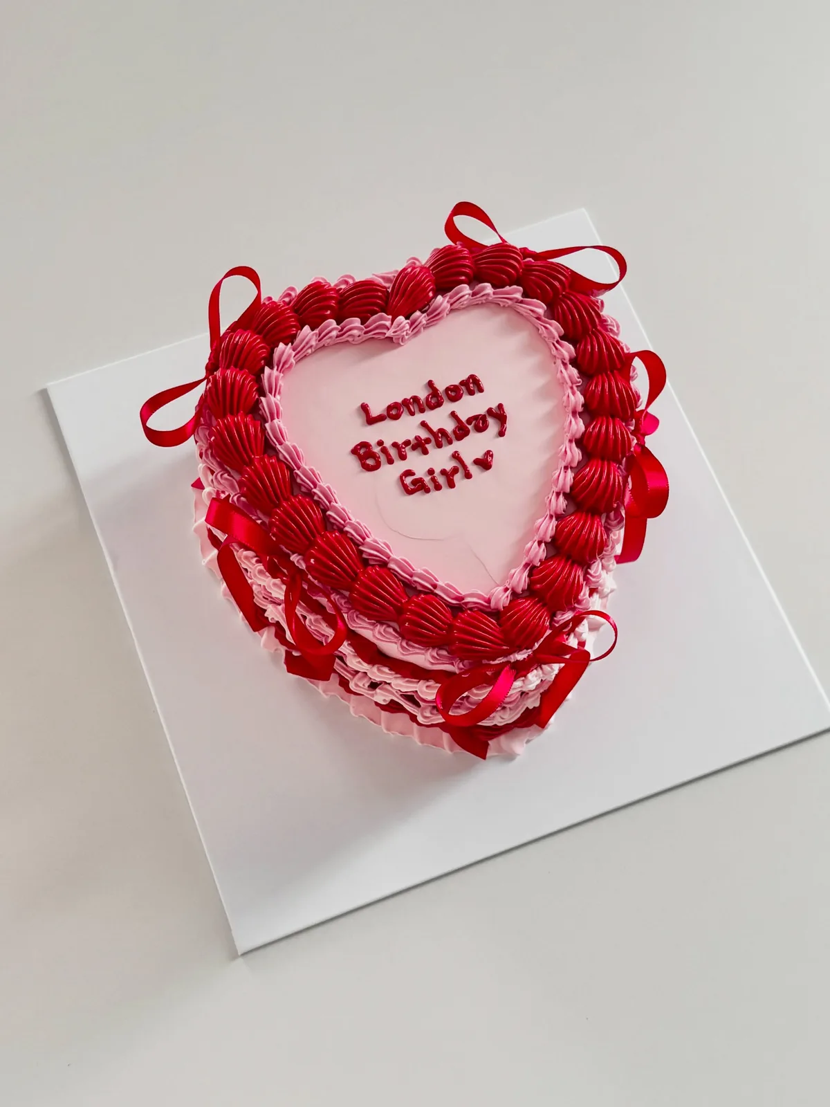 Red heart cake with ribbons and piped lace, handmade to order by Danine Cakes in Streatham, South London