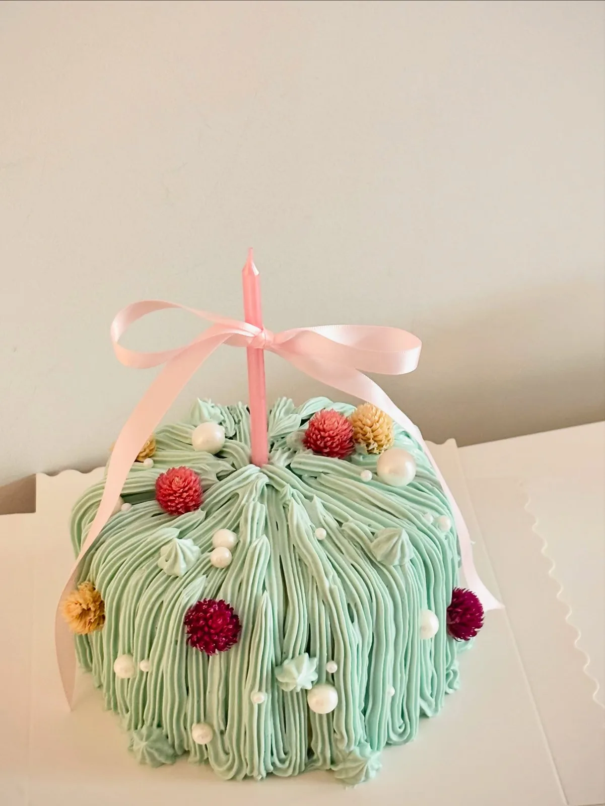 Sage green piped strand cake with dried flowers and pink ribbon, custom cake made in Streatham SW16 - Danine Cakes
