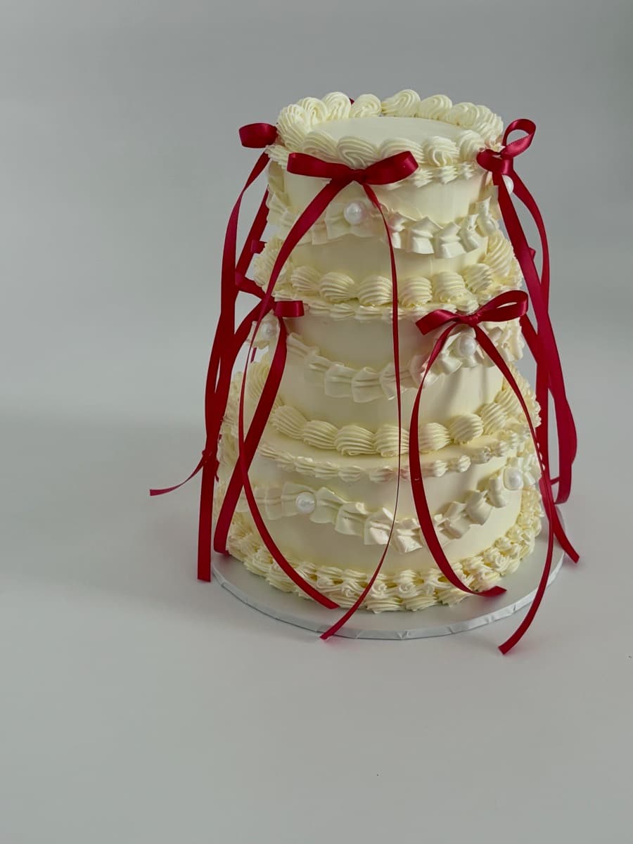 Three-tier ivory wedding cake, crimson ribbons