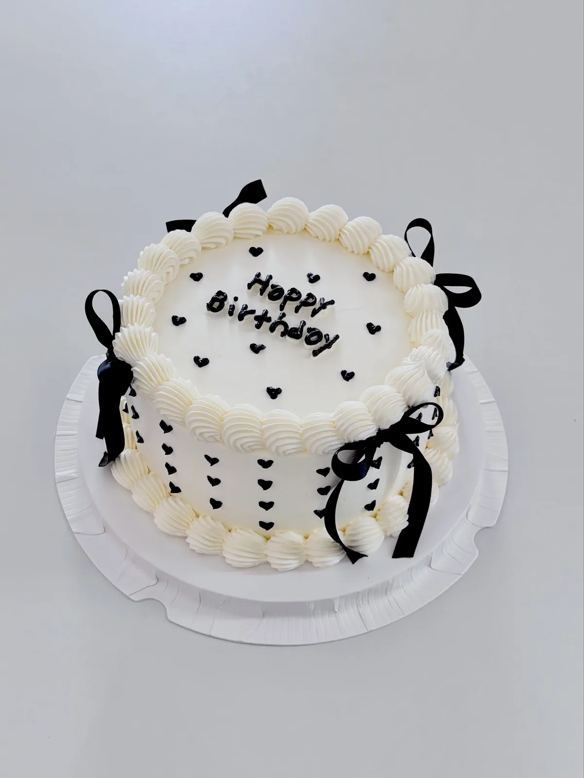 White cake with black hearts, bows and lettering, Korean-inspired custom cake handmade in Streatham, London