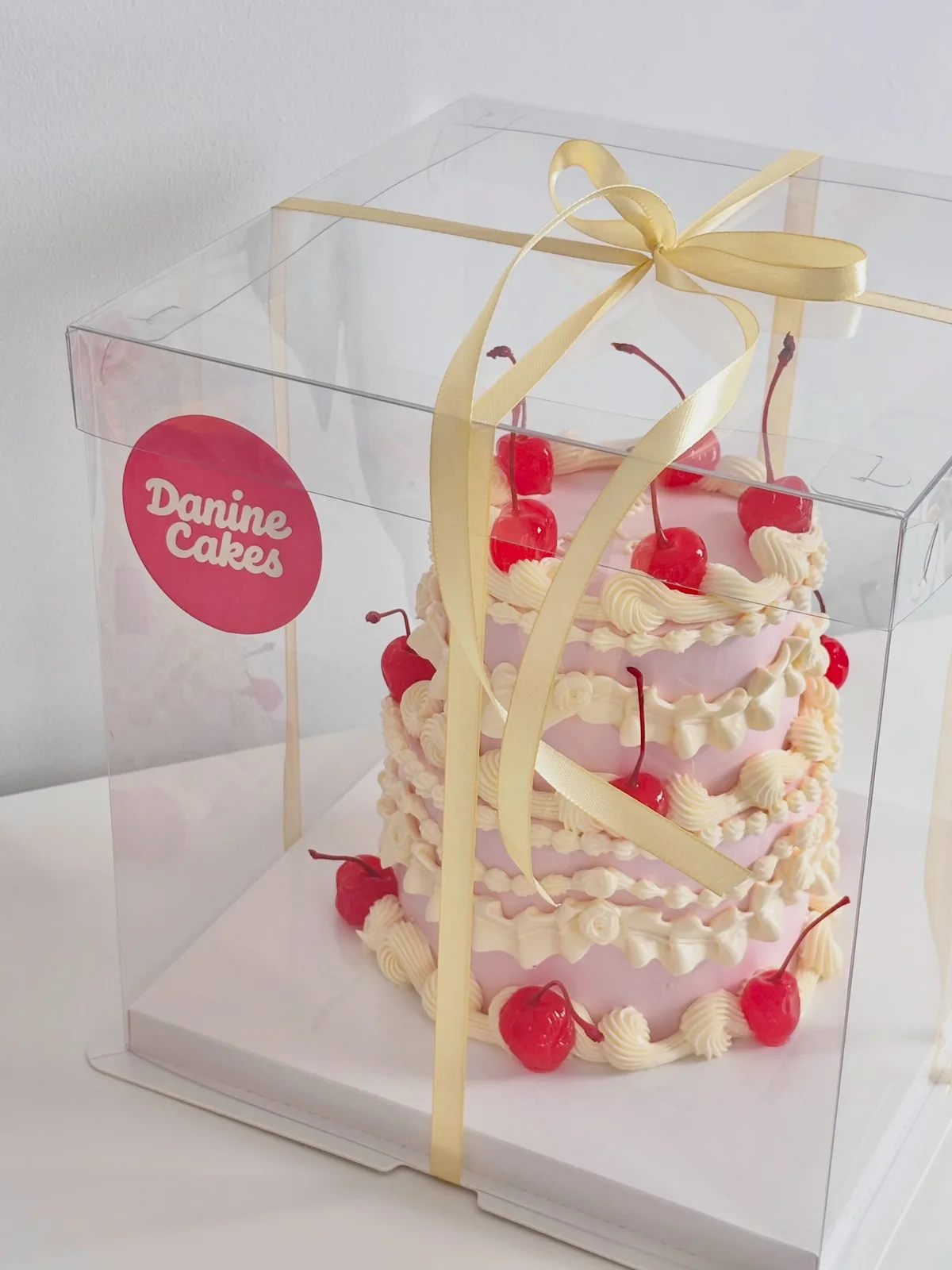 White cake with cherries and yellow ribbon in a box, Korean-inspired custom cake handmade in Streatham, London