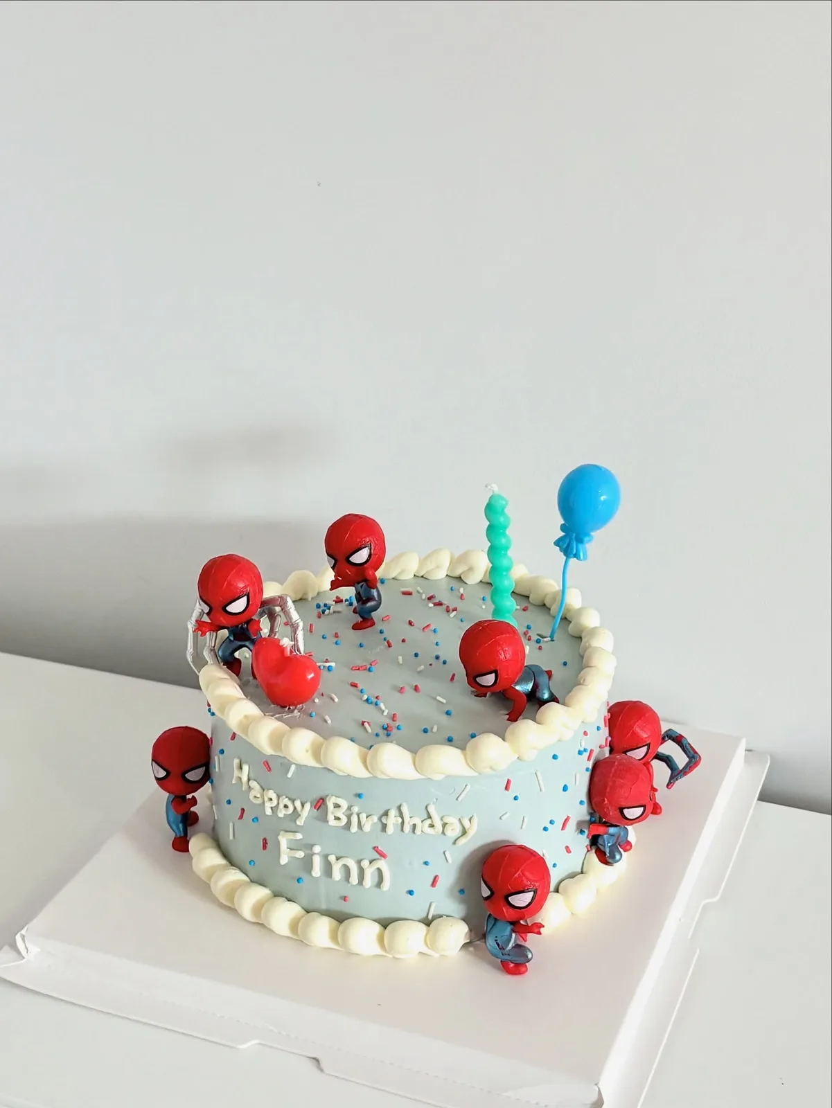 White cake with superhero figures and balloons, bespoke celebration cake from Danine Cakes, South London