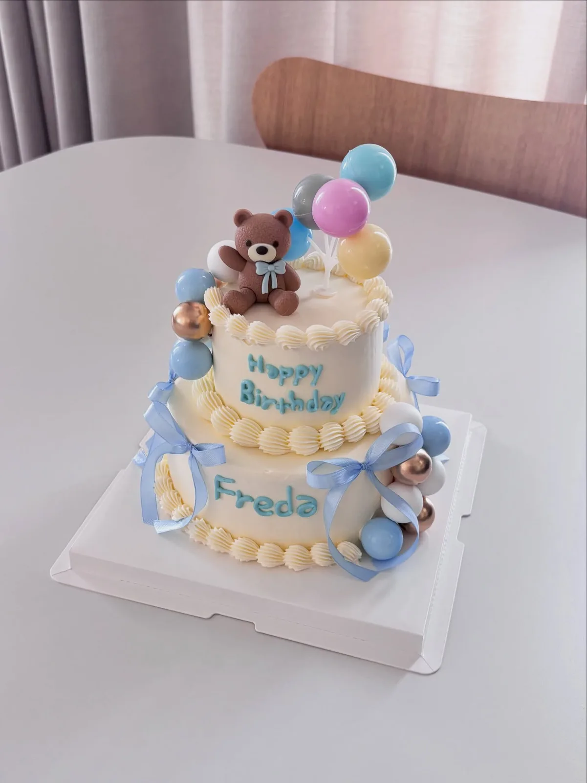 White cake with teddy bear and balloon toppers, bespoke celebration cake from Danine Cakes, South London
