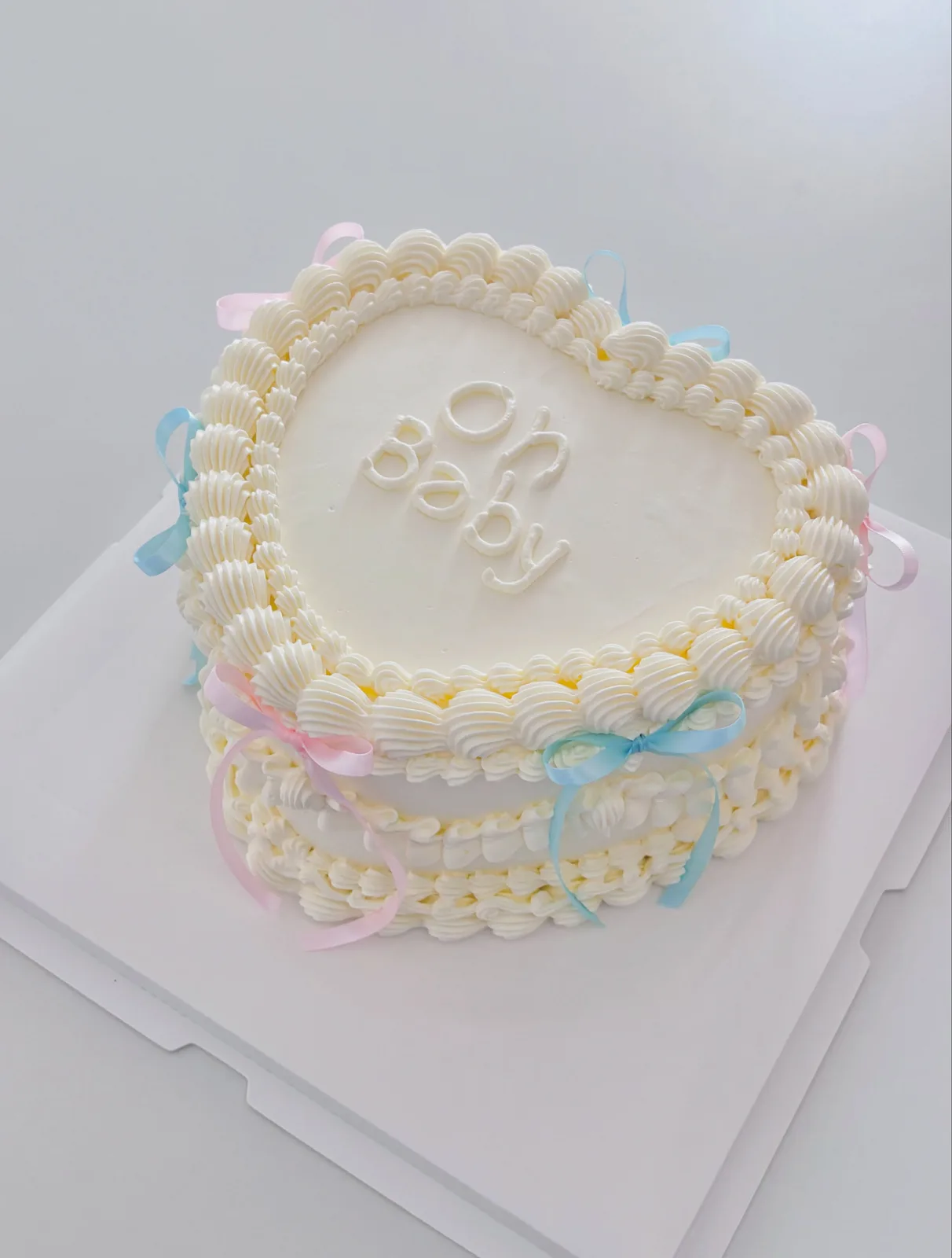 White heart cake with pastel ribbons and piped border, handmade to order by Danine Cakes in Streatham, South London