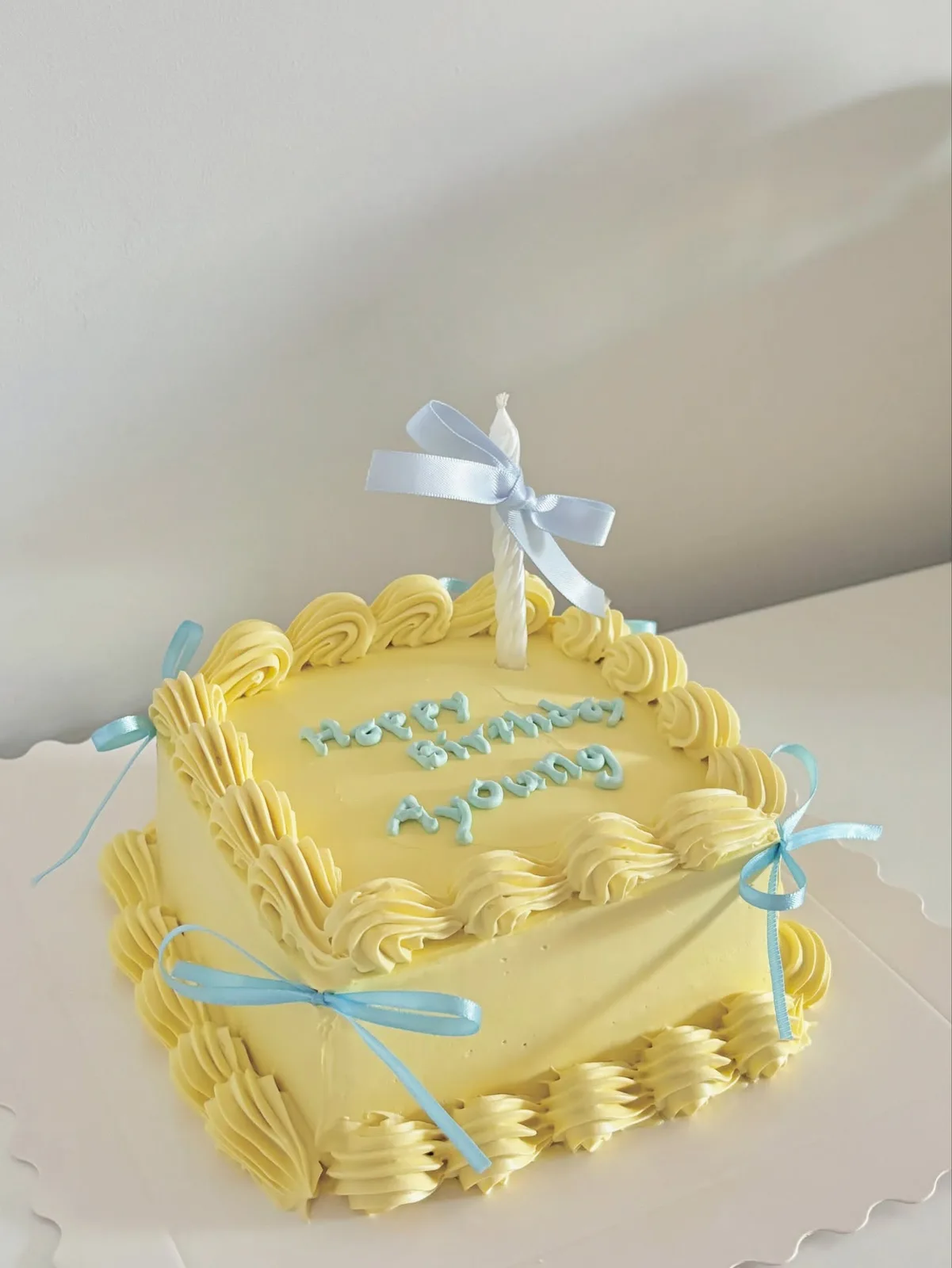 Yellow cake with blue satin bow and piped border, handmade to order by Danine Cakes in Streatham, South London
