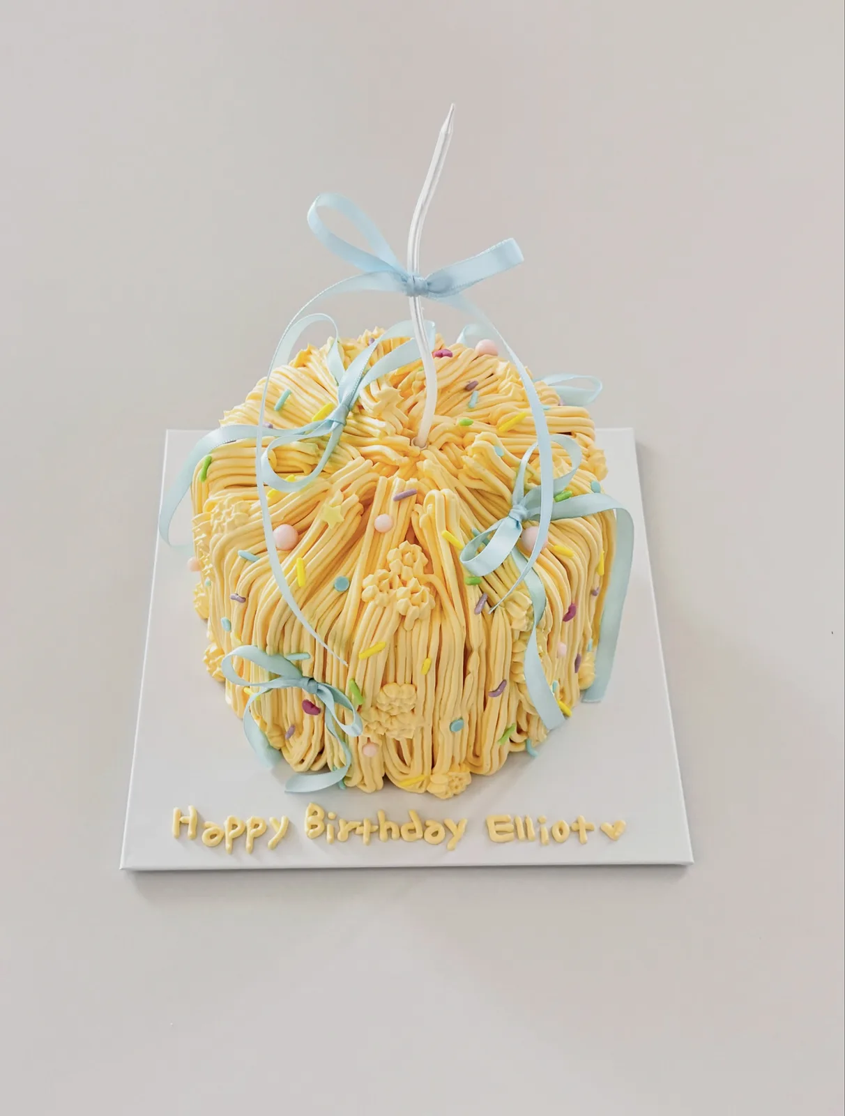 Yellow piped strand cake with blue ribbon, bespoke celebration cake from Danine Cakes, South London
